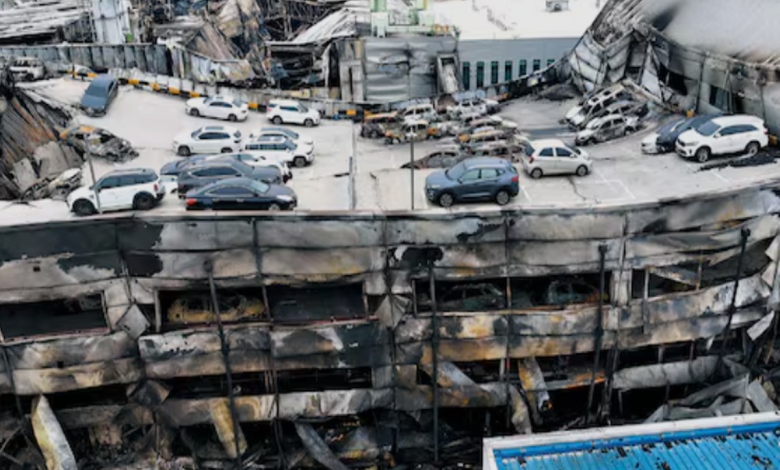 대형 화재 현장에서 검은 연기가 치솟고 소방대원들이 긴급 진압을 시도하는 장면